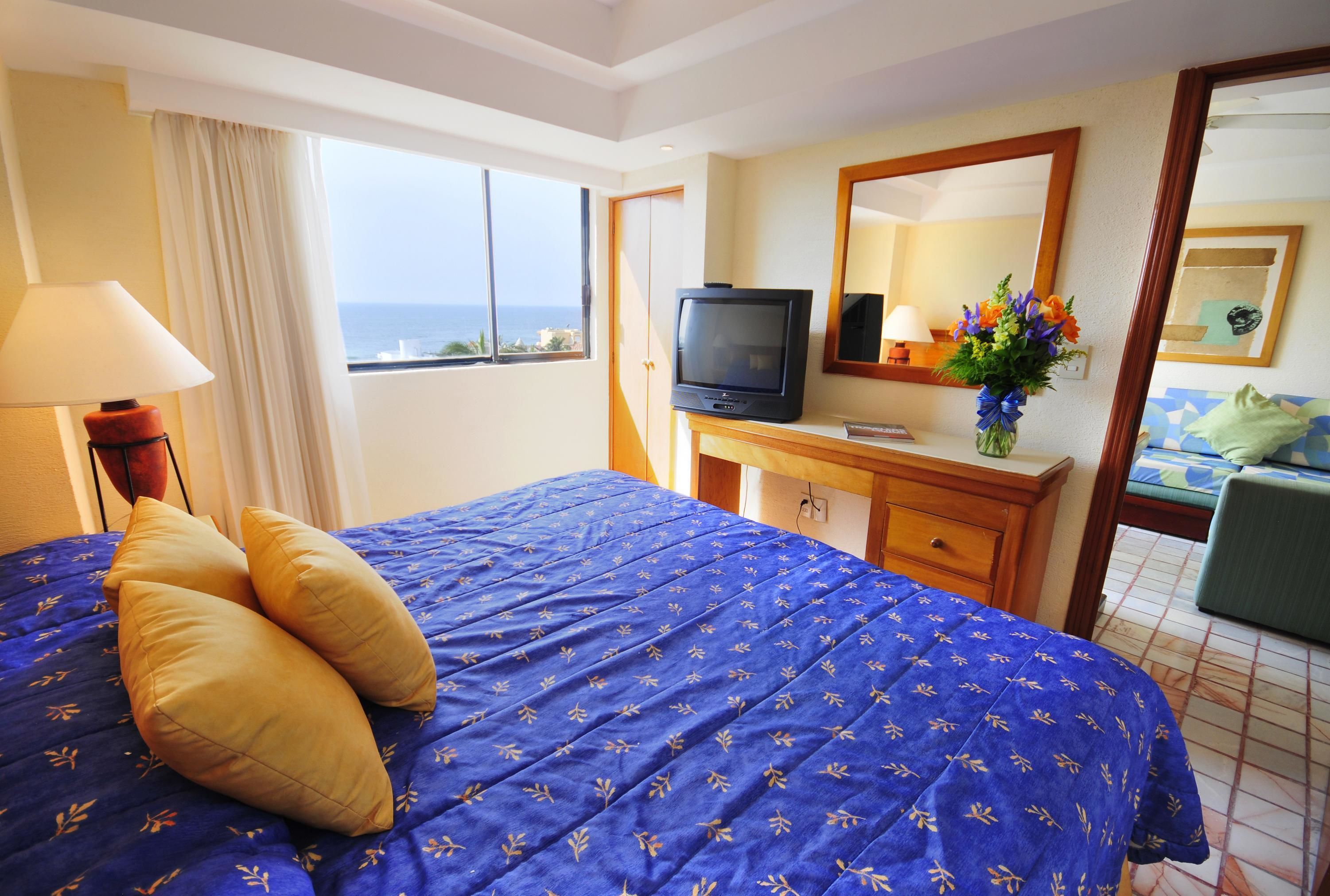 Habitación de hotel con una cama grande, televisión, escritorio y vistas al océano.