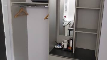 Un dressing avec un miroir, des étagères et une petite table sur laquelle se trouve une machine à café.