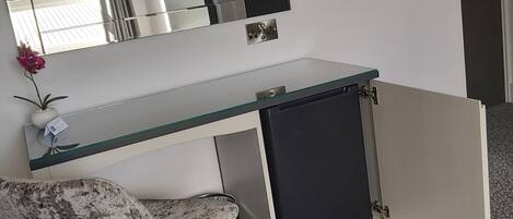 A modern office desk with a glass top, a chair, and a cabinet.