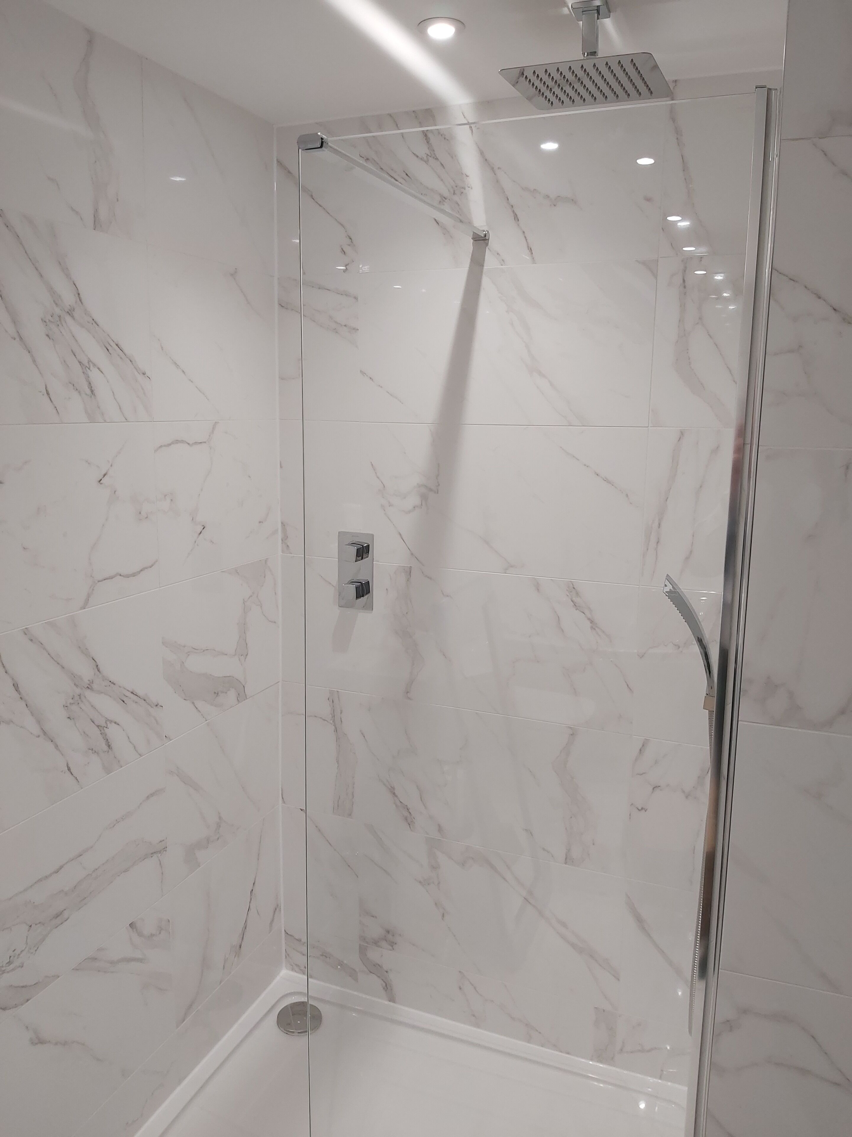 A modern shower enclosure with a glass door and a rain showerhead.