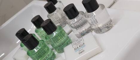 Un estante de baño con varias botellas de jabón de alga marina y una pastilla de jabón blanca.
