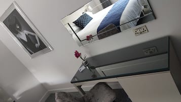 A modern hotel room with a bed, a desk, and a chair.