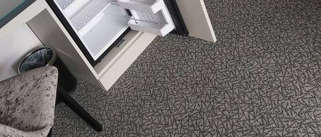 Una habitación con escritorio, silla y piso alfombrado.