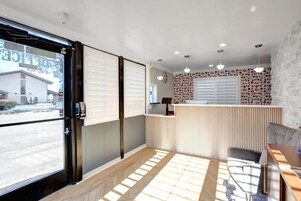 Una habitación con puerta corredera, una recepción, un papel tapiz decorado y una ventana con persianas.
