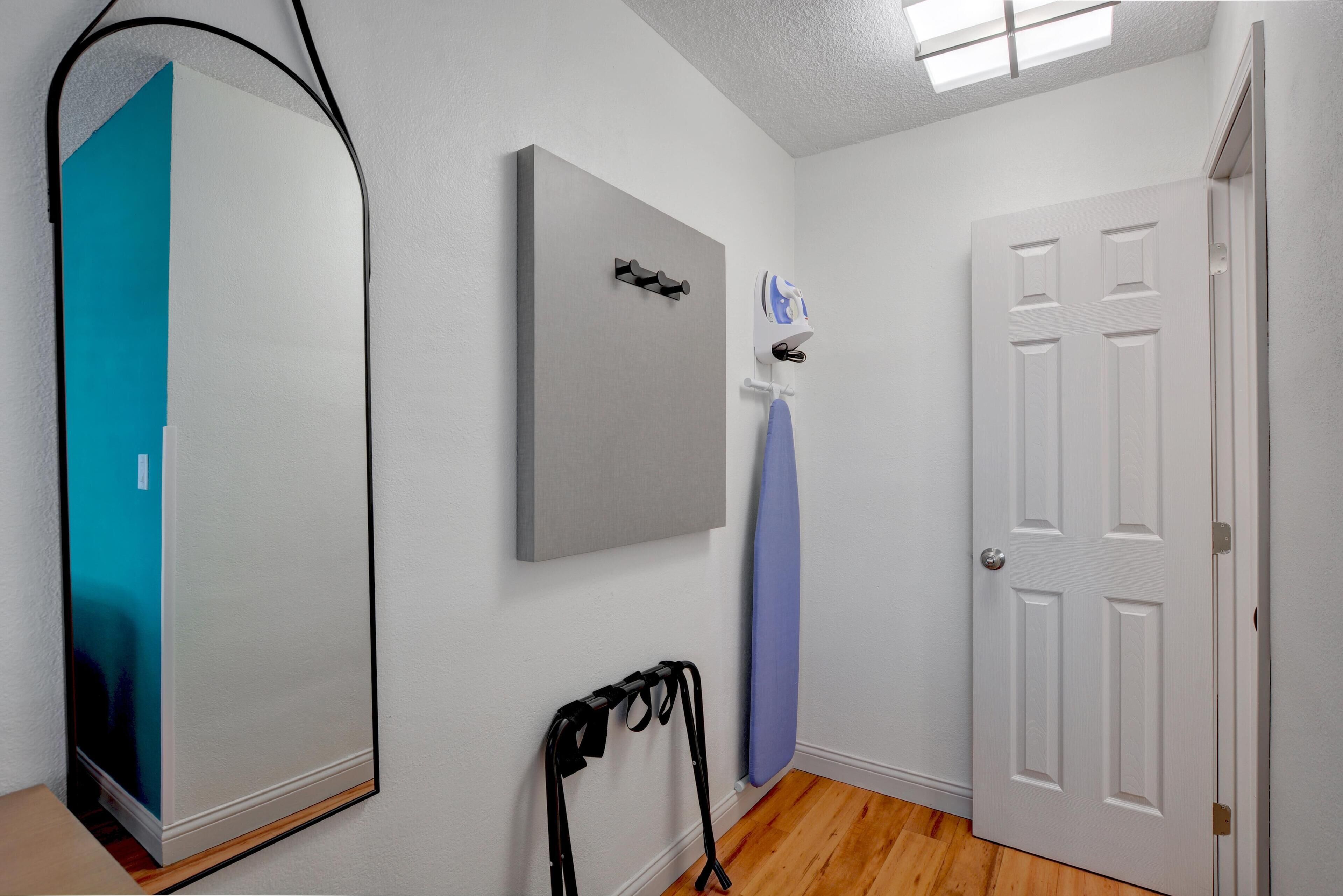 A room with a white door, a grey wall-mounted item, a blue curtain, and a black object on the floor.