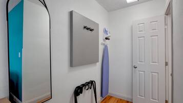 A room with a white door, a grey wall-mounted item, a blue curtain, and a black object on the floor.