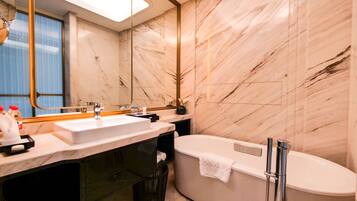 Un baño moderno con un espejo grande, dos lavamanos, una bañera y paredes de mármol.