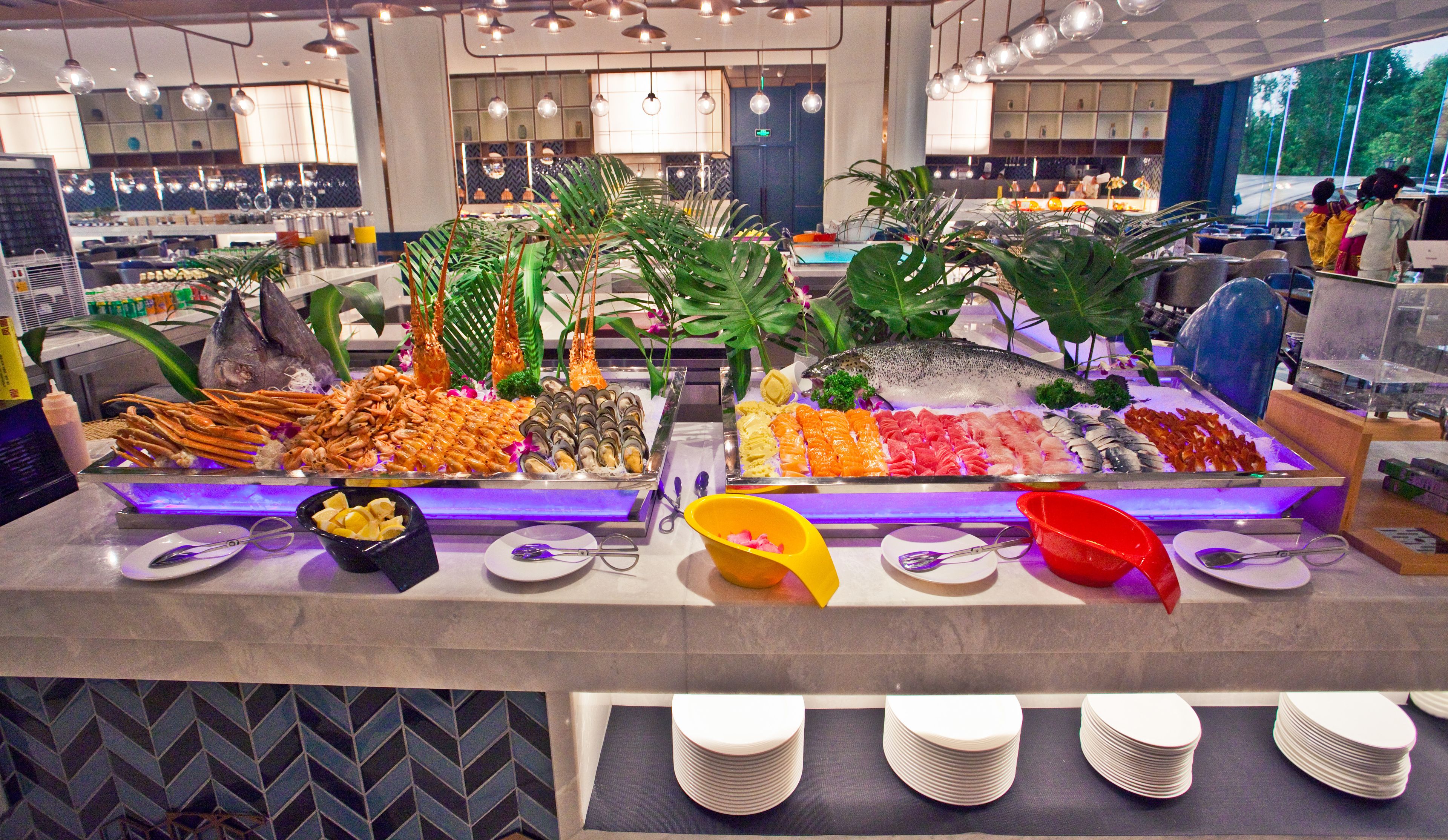 A buffet with seafood, tropical plants, and a variety of dishes.