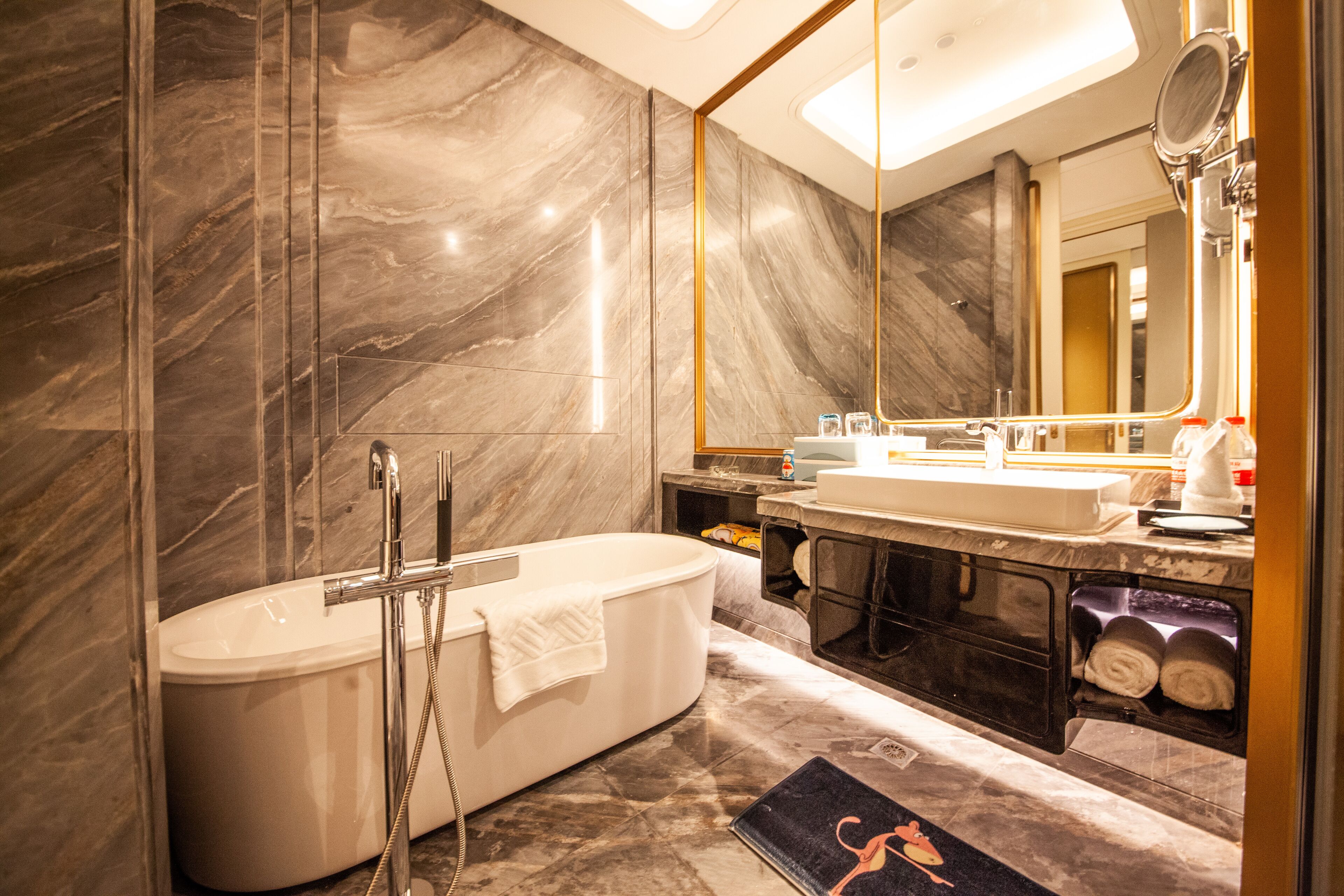 A modern bathroom with a freestanding bathtub, a large mirror, and a vanity with a sink and towel rack.