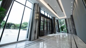 Un hall moderno de hotel con ventanas amplias, piso pulido y una zona de recepción.