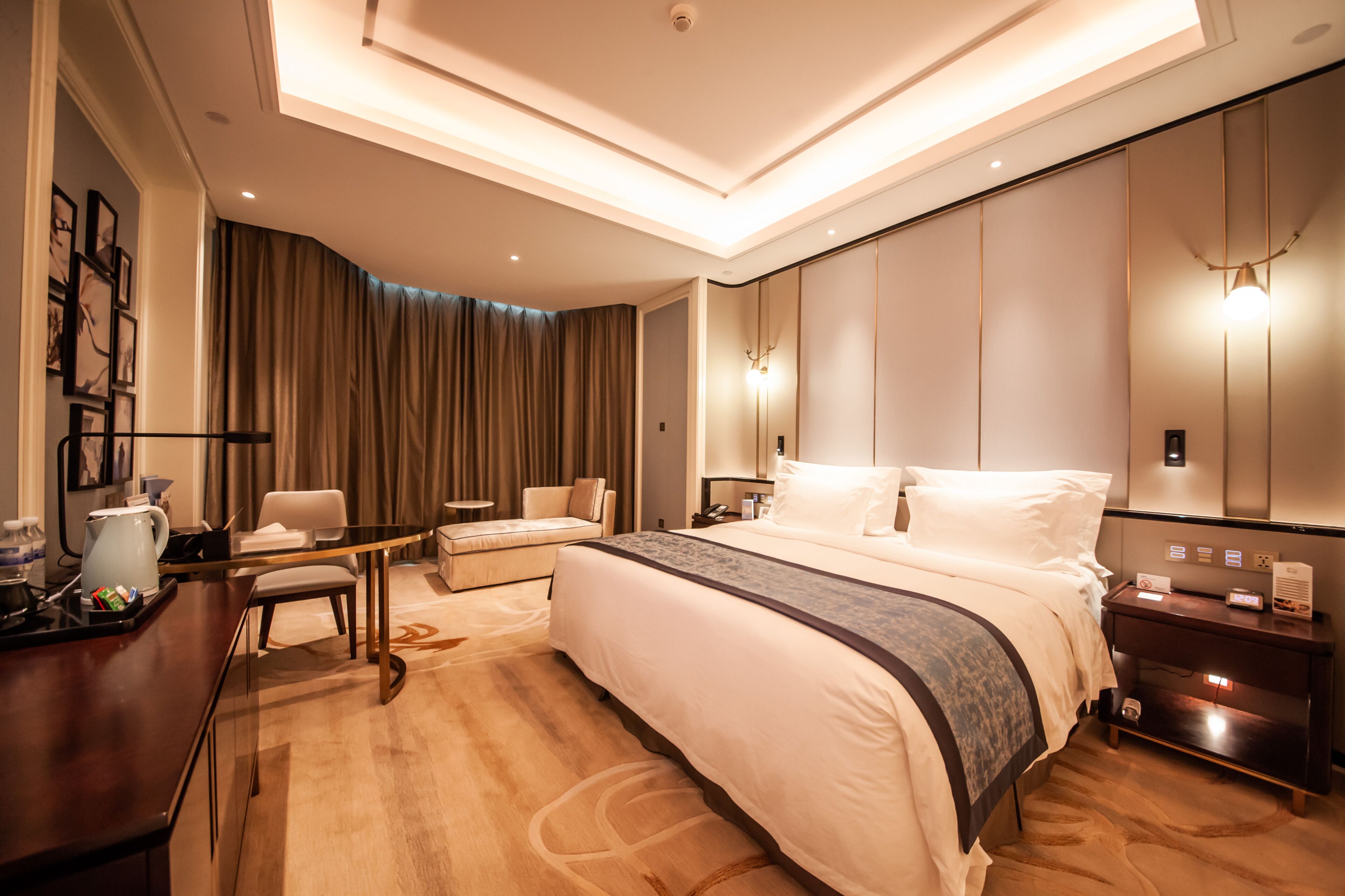 Habitación de hotel moderna con una cama grande, un escritorio, una silla y una mesita de noche con lámpara.