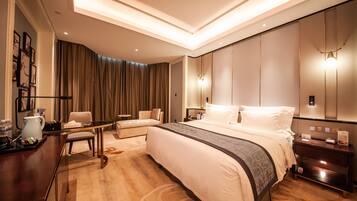 Habitación de hotel moderna con una cama grande, un escritorio, una silla y una mesita de noche con lámpara.