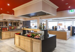 Una cocina moderna con una isla central, armarios de madera y una encimera de vidrio que exhibe alimentos.
