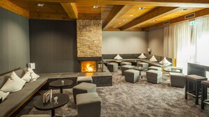 A modern lounge area with a stone fireplace, comfortable seating, and a carpeted floor.