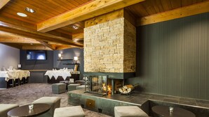 A cozy lounge area with a stone fireplace, comfortable seating, and a television screen.
