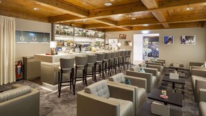 A bar area with a long counter, multiple bar stools, and a seating area with sofas and tables.