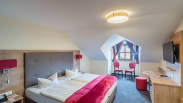 A hotel room with a large bed, a desk, a TV, and a view of the outside.