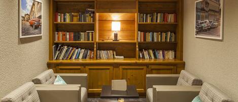 Une salle de lecture chaleureuse, avec des étagères en bois, deux canapés et une table basse.