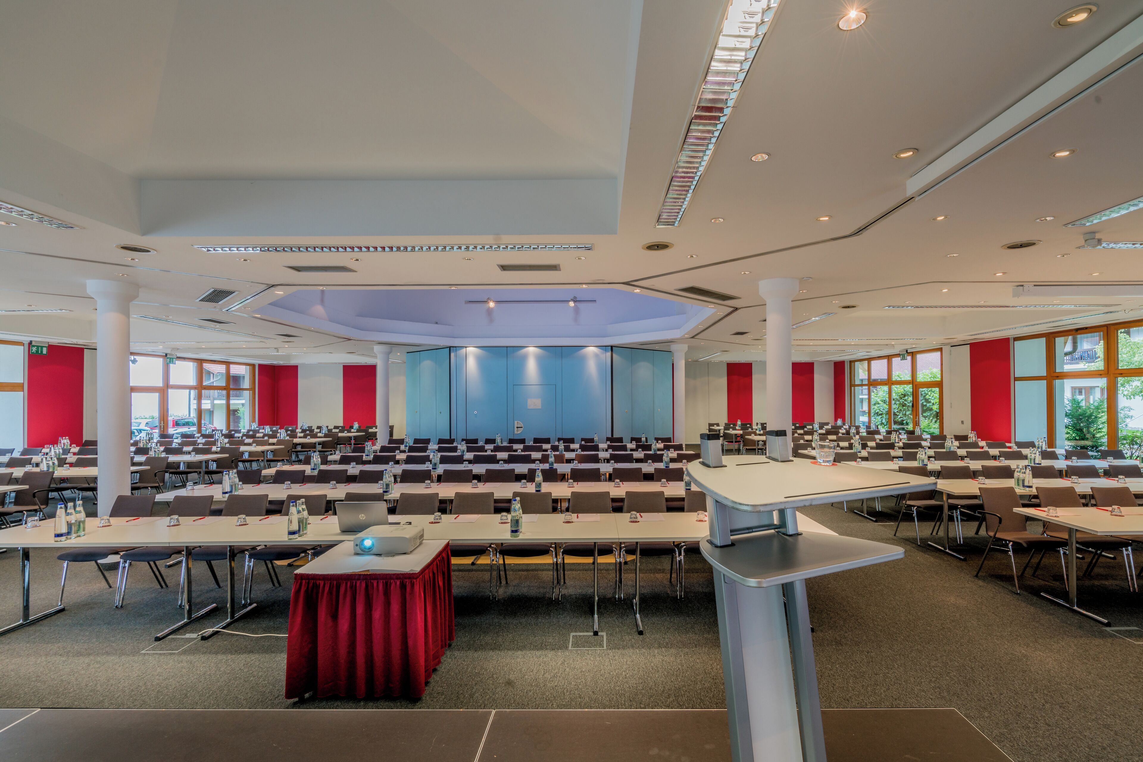 Una sala conferenze con diversi tavoli, sedie e un palco.