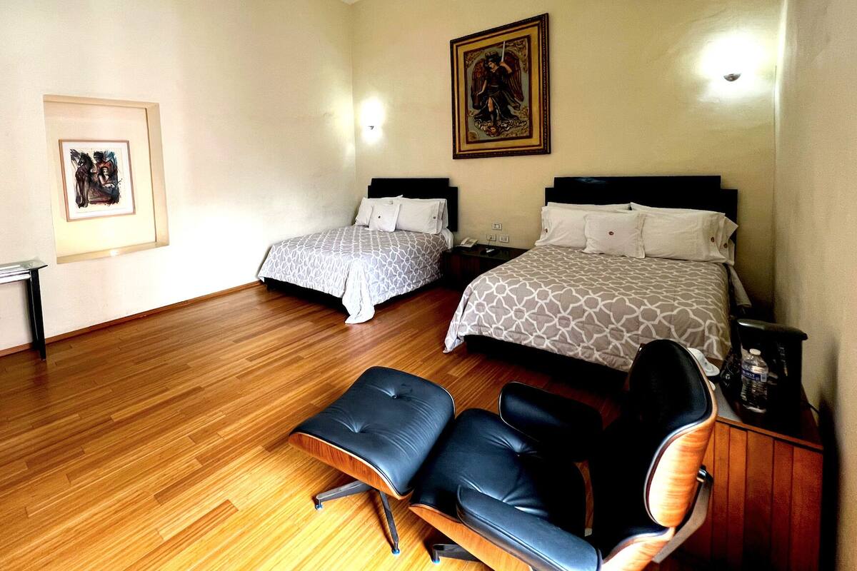 Habitación de hotel con dos camas, un escritorio y una silla.