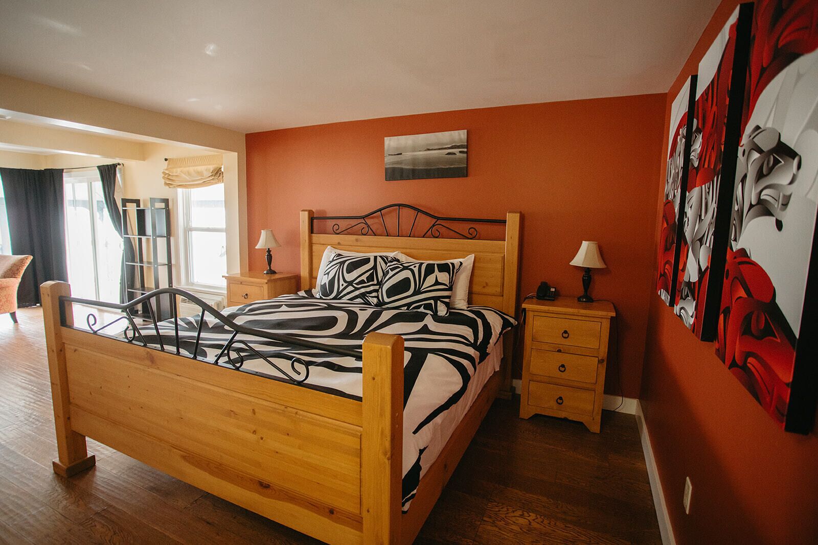 Un dormitorio con una cama de madera, dos mesitas de noche y un cuadro abstracto grande en la pared.