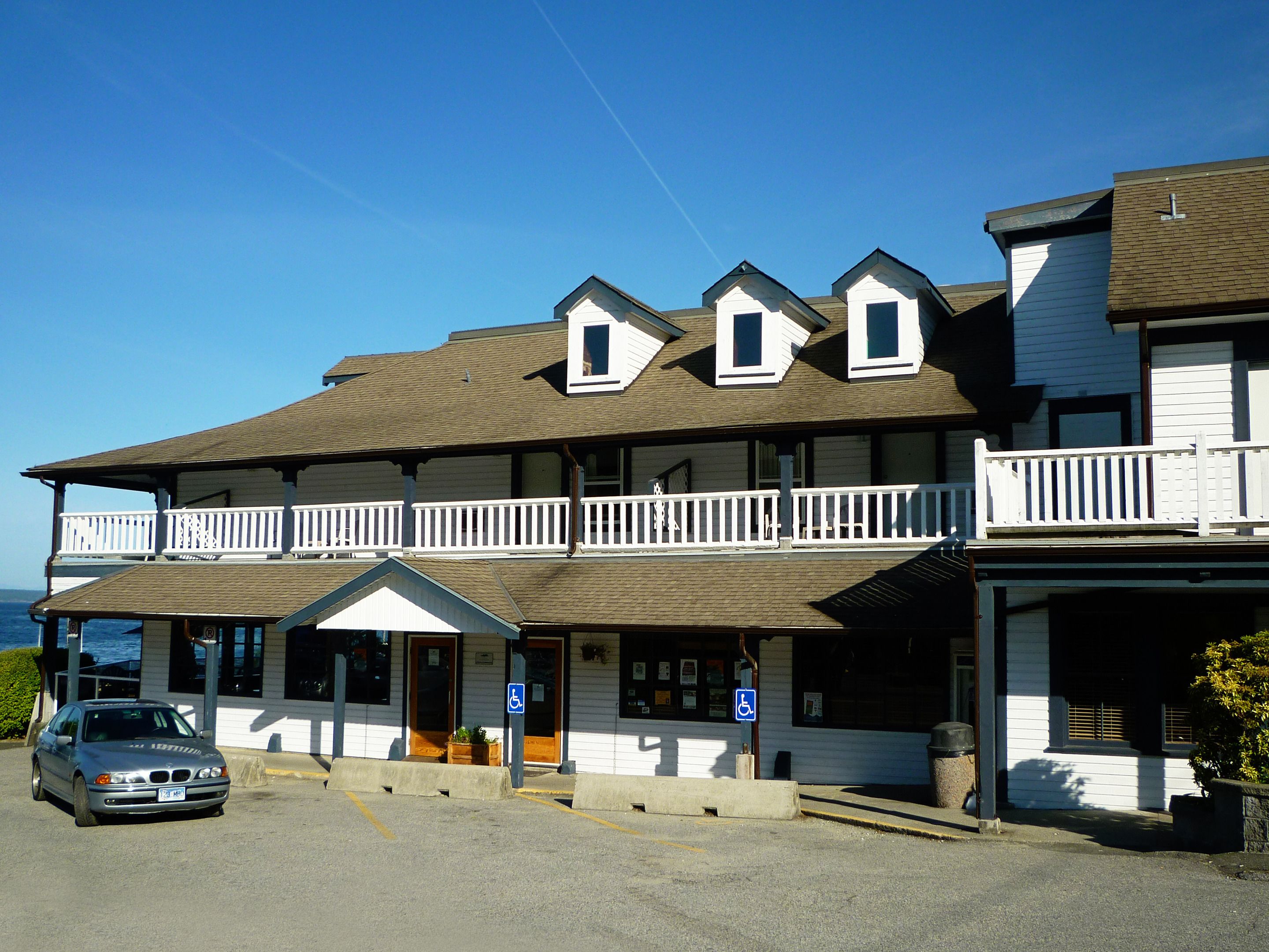 A two-story building with a balcony, a parking lot, and a sign indicating handicap accessibility.