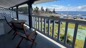 A covered outdoor seating area with a table and chairs, overlooking a marina with boats and a clear sky. - The Lund Resort at Klah ah men (Lund)