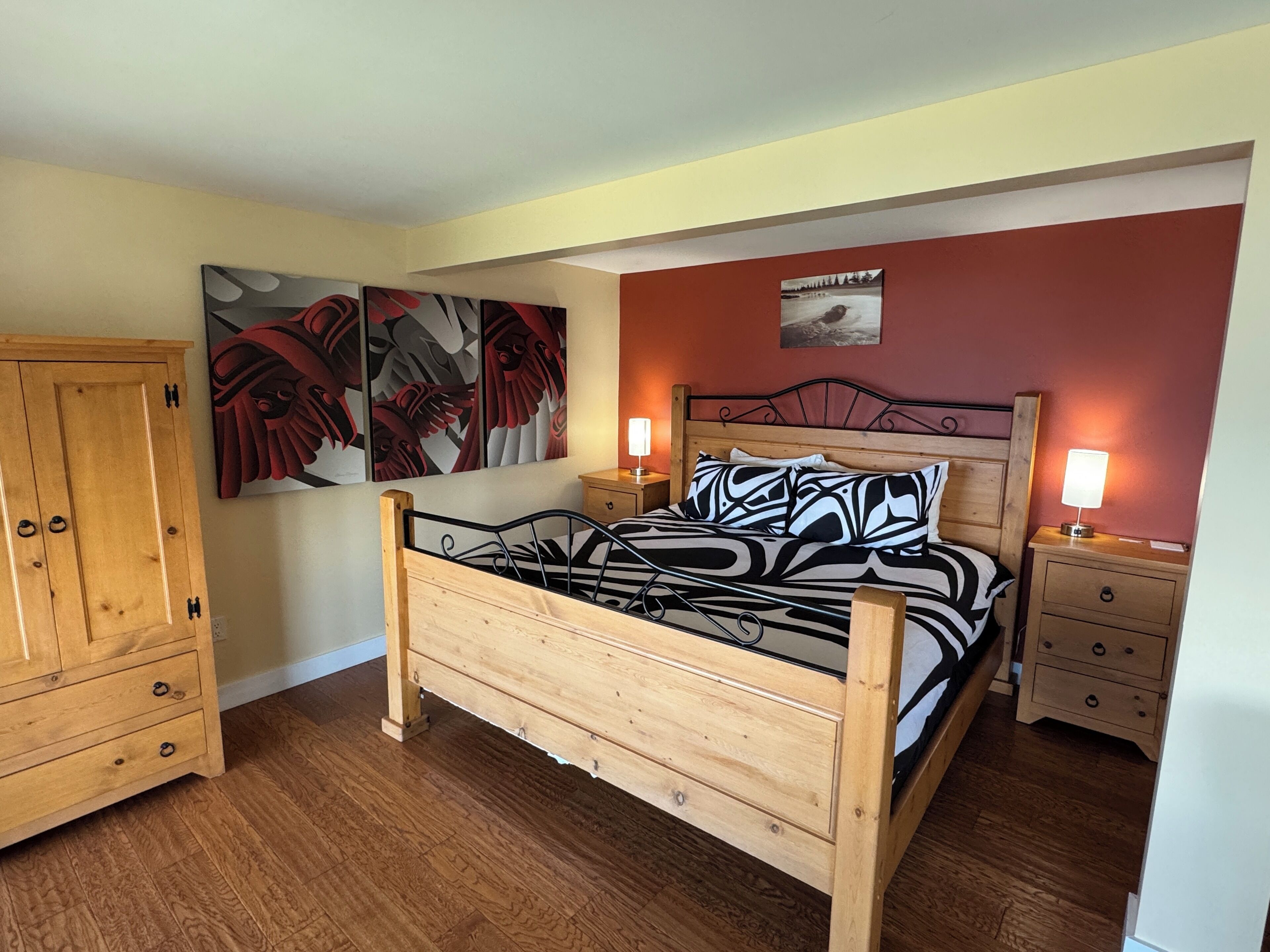 Un dormitorio con una cama de madera, dos mesitas de noche, un armario y dos lámparas fijadas a la pared.