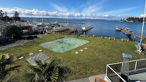 A marina with boats docked, a grassy area with a colorful mural, and a clear view of the water and distant land. - The Lund Resort at Klah ah men (Lund)