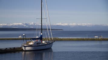 A sailboat docked near a calm body of water with a mountainous landscape in the background.