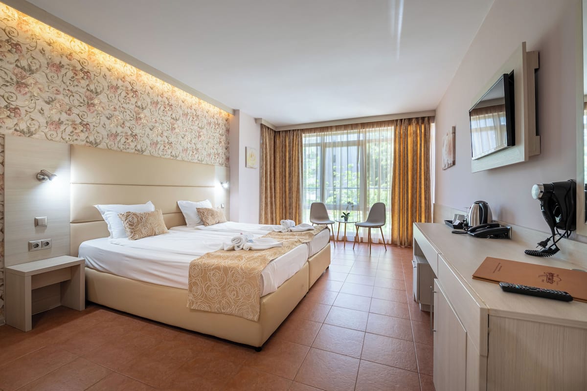 A hotel room with a large bed, a desk, a chair, and a TV.