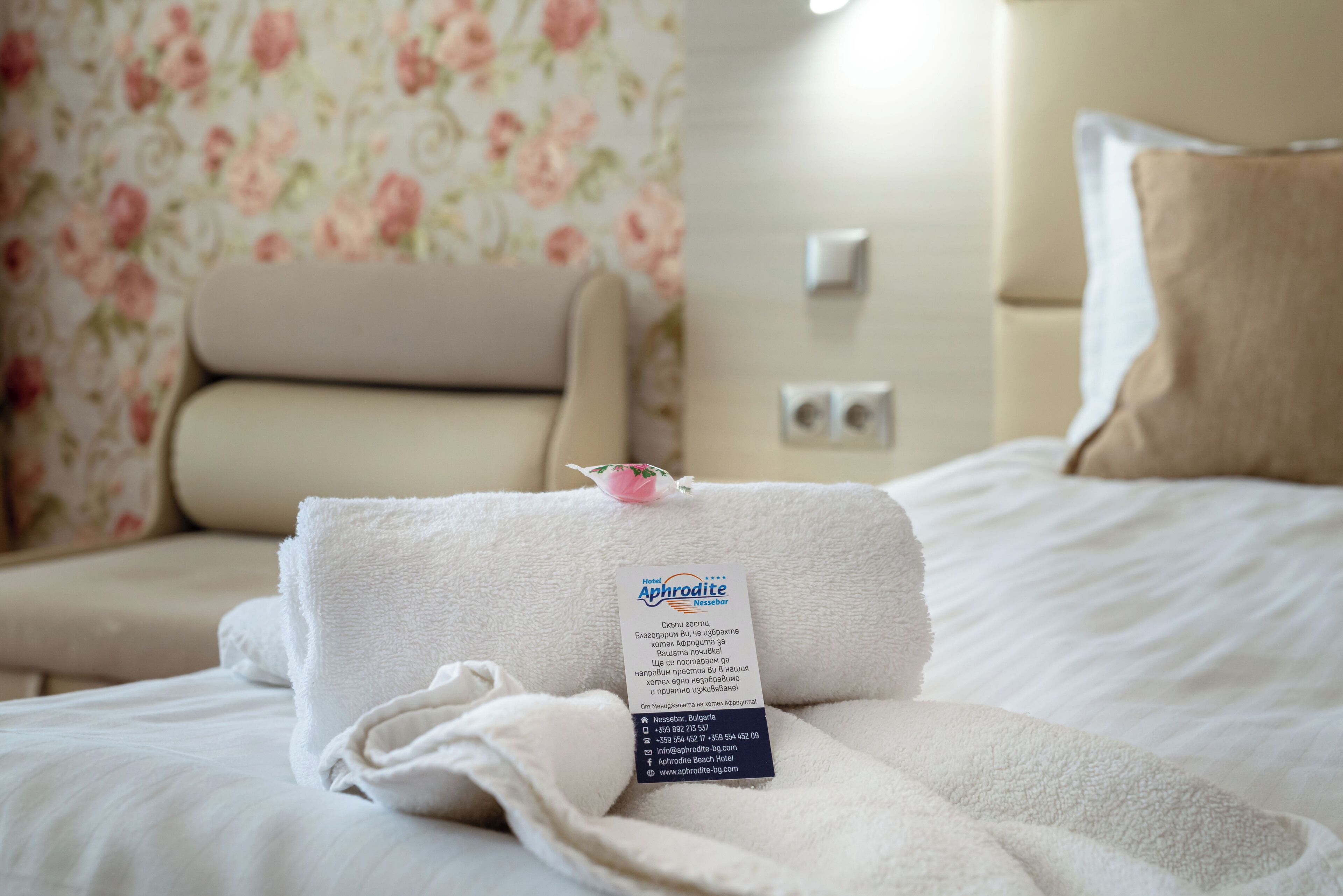 A neatly made bed with a folded towel and a tag indicating the hotel name and amenities.