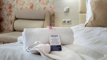 A neatly made bed with a folded towel and a tag indicating the hotel name and amenities.