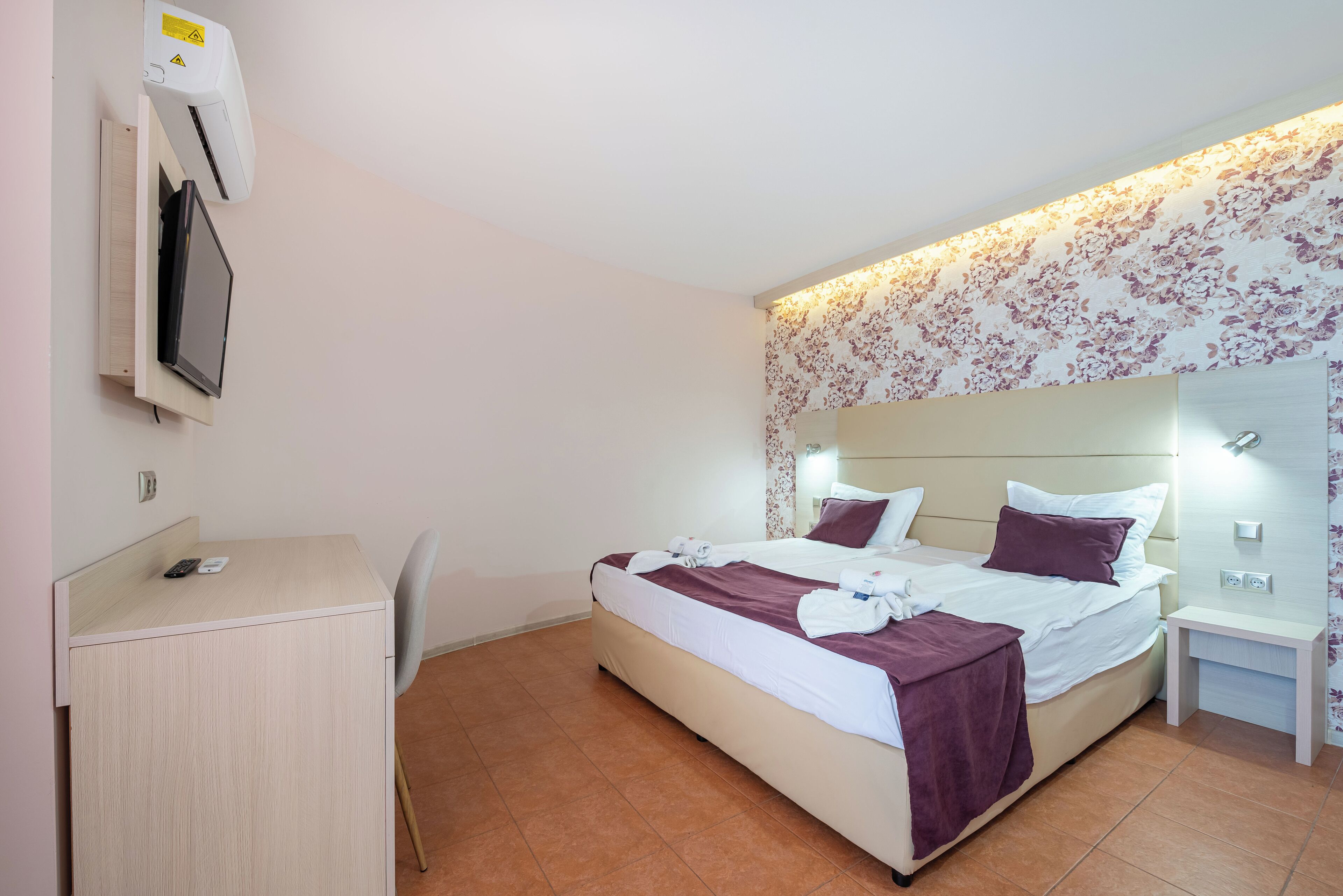 Una camera d'albergo con un letto, comodini, una scrivania e una sedia.