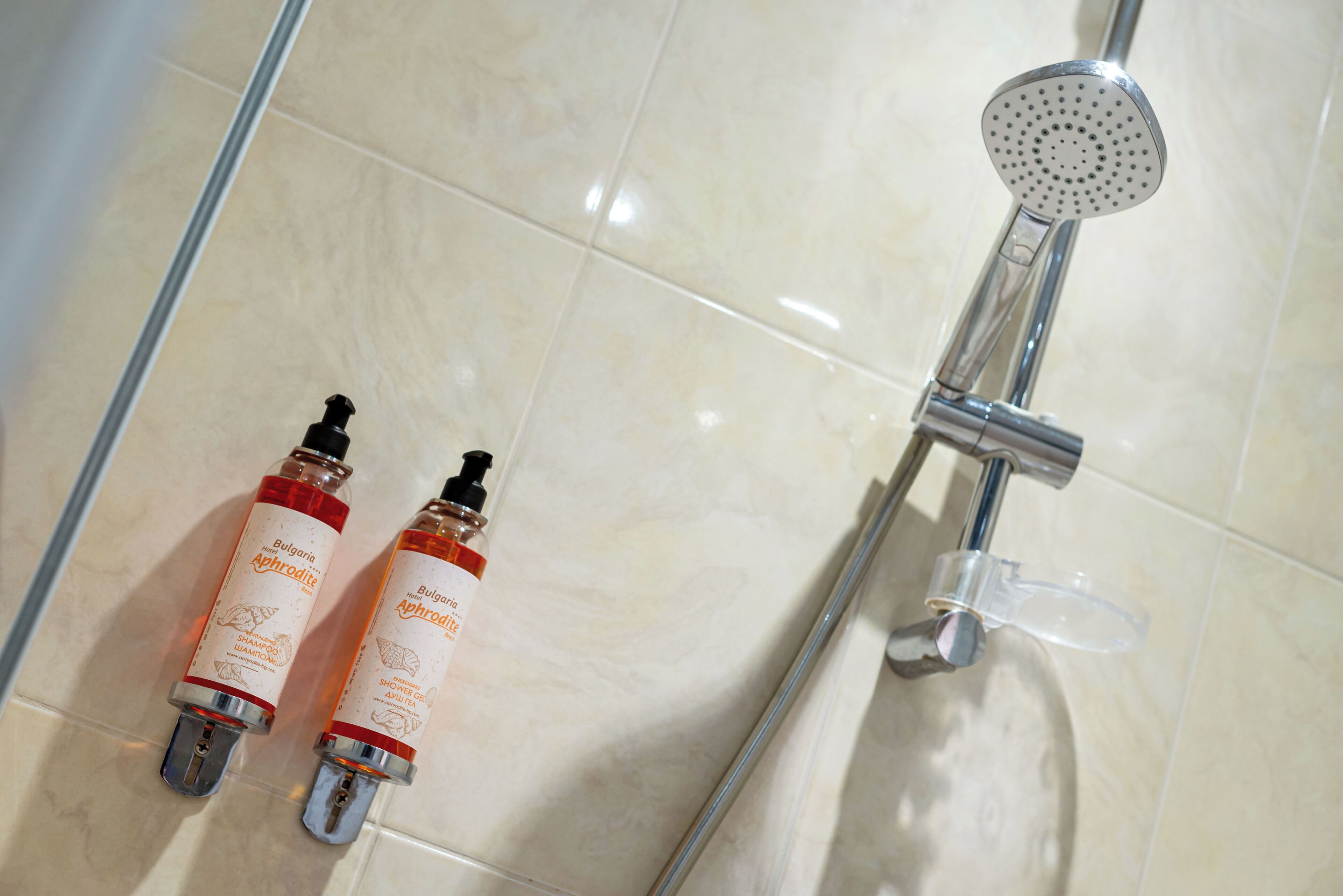 Une salle de bain avec une douche, deux bouteilles de shampoing et un pommeau de douche amovible.
