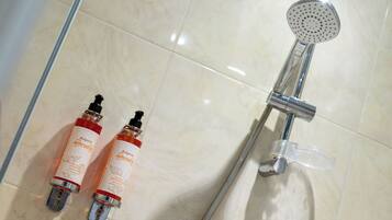 Une salle de bain avec une douche, deux bouteilles de shampoing et un pommeau de douche amovible.