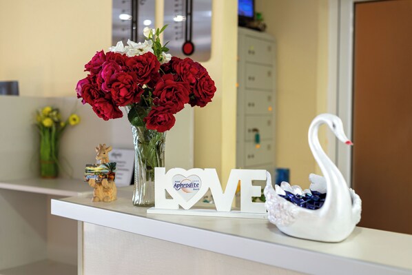Una recepción con un jarrón de rosas rojas, una decoración de cisne y un cartel que dice 'LOVE'.