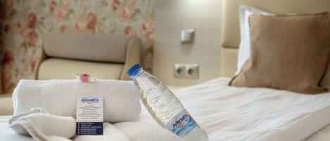 Una cama bien hecha con una botella de agua y una toalla.