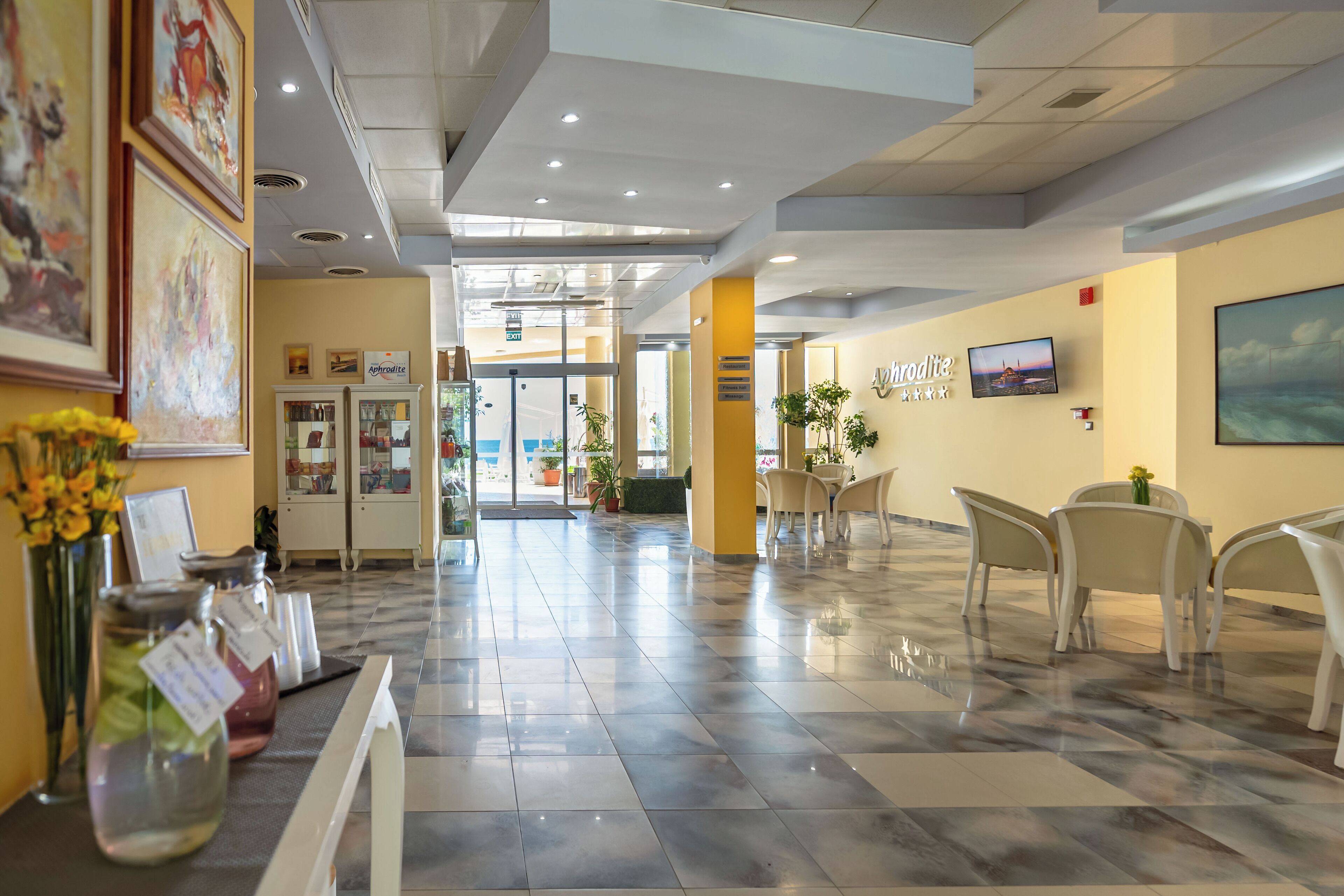 A hotel lobby with a marble floor, a reception desk, and a seating area with chairs.
