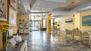 A hotel lobby with a marble floor, a reception desk, and a seating area with chairs.