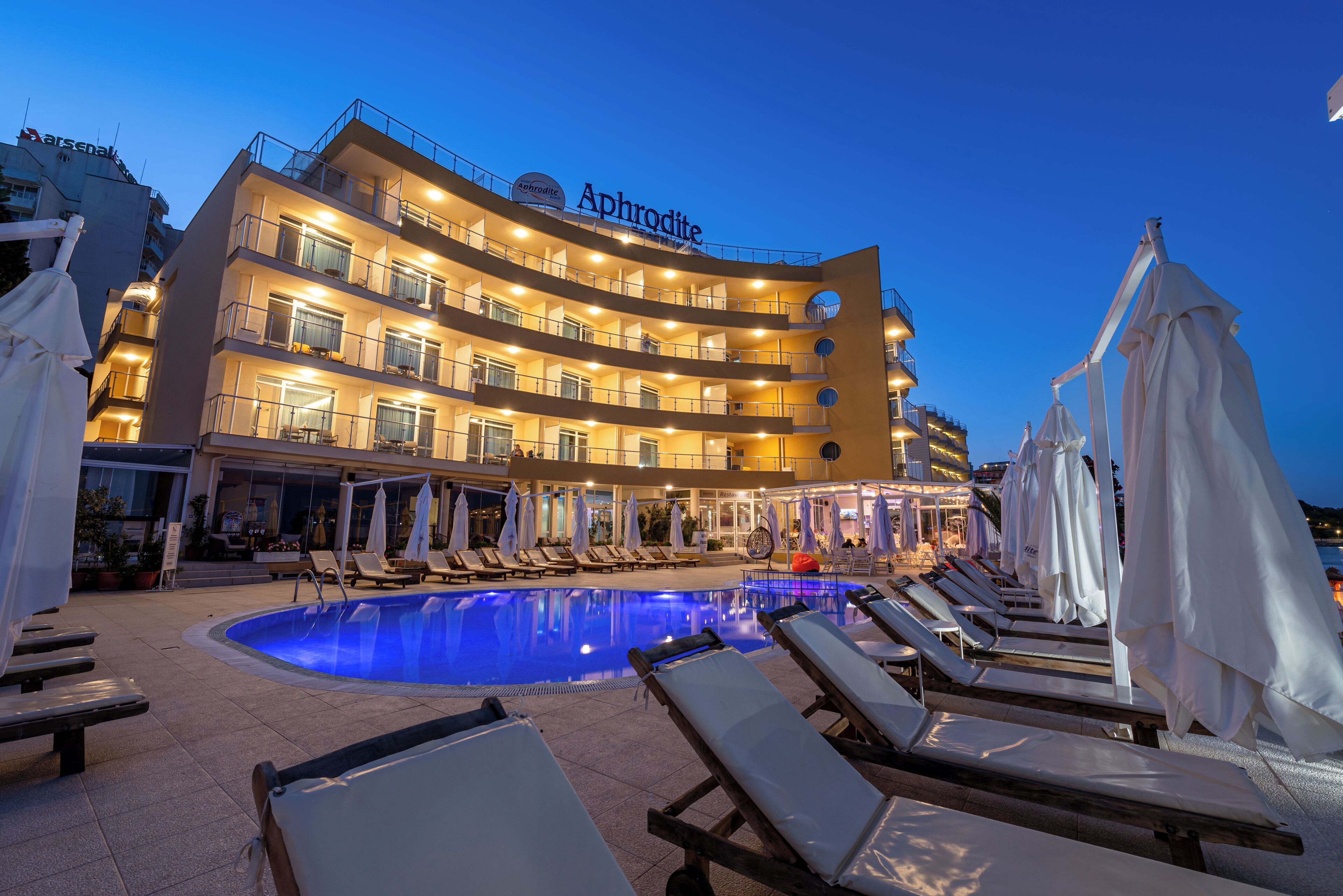 Un hotel con piscina, tumbonas y un cartel que dice "Aphrodite".