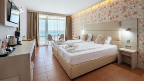 Habitación de hotel con dos camas, un escritorio con hervidor, una silla y vistas al exterior.