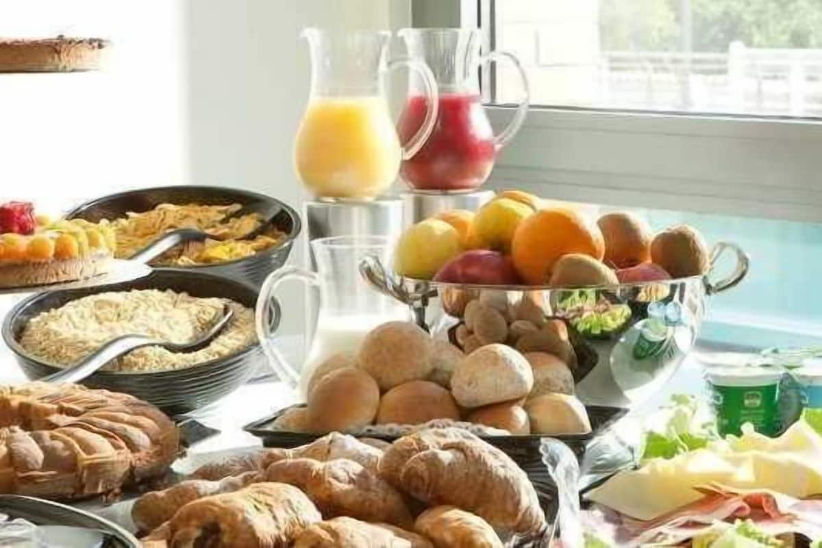 Un bufé de desayuno con diversas opciones de comida, como frutas, pasteles y bebidas.