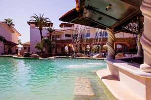 A pool area with a water fountain, palm trees, and buildings with arched walkways. - Los Cabos Golf Resort, Trademark Collection by Wyndham (Cabo San Lucas)