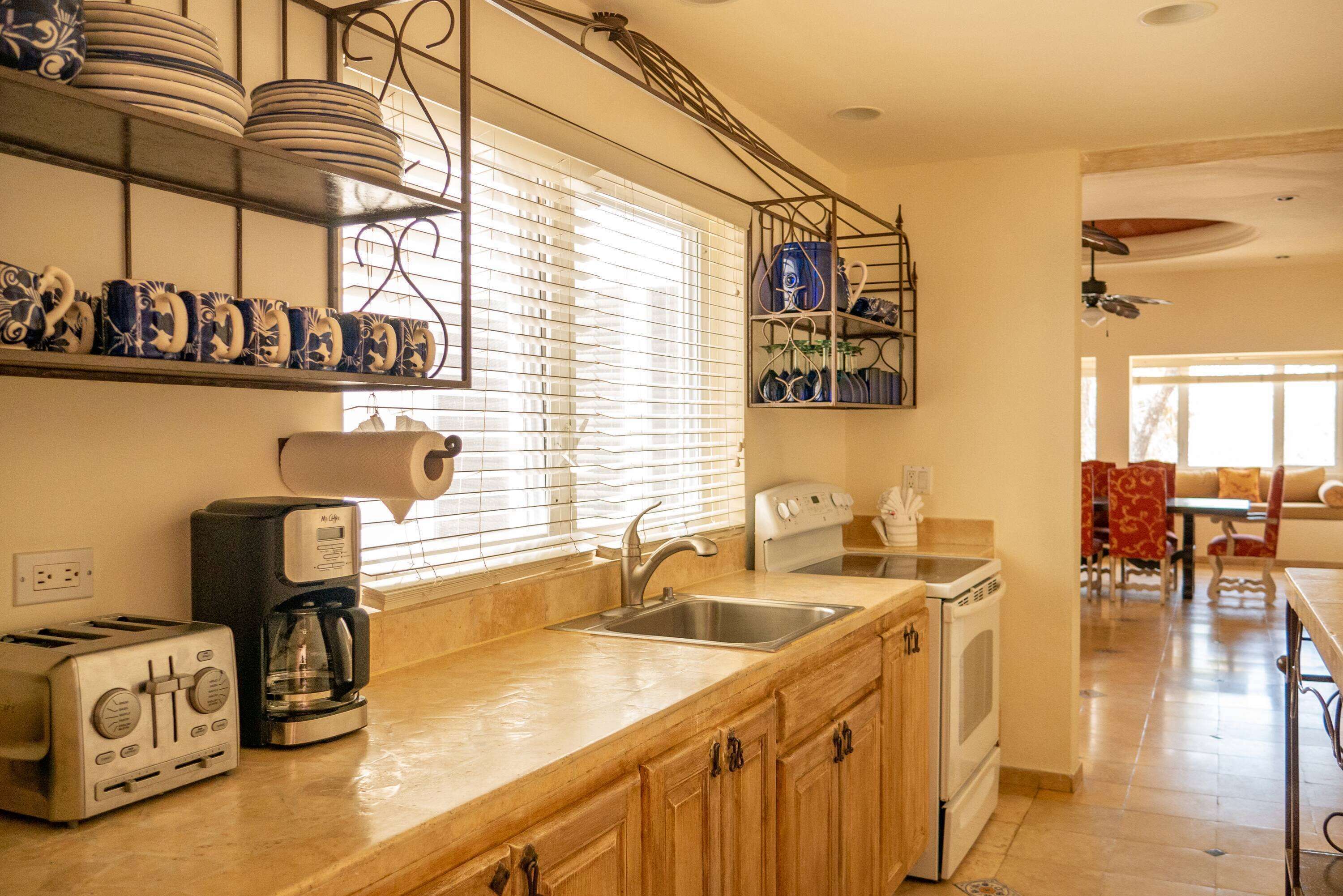 A kitchen with a toaster, coffee maker, sink, and cabinets.