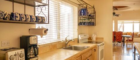 A kitchen with a toaster, coffee maker, sink, and cabinets.