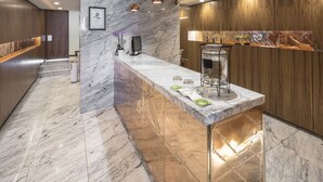 Une cuisine moderne dotée d’un plan de travail en marbre, de lambris en bois et de luminaires suspendus.
