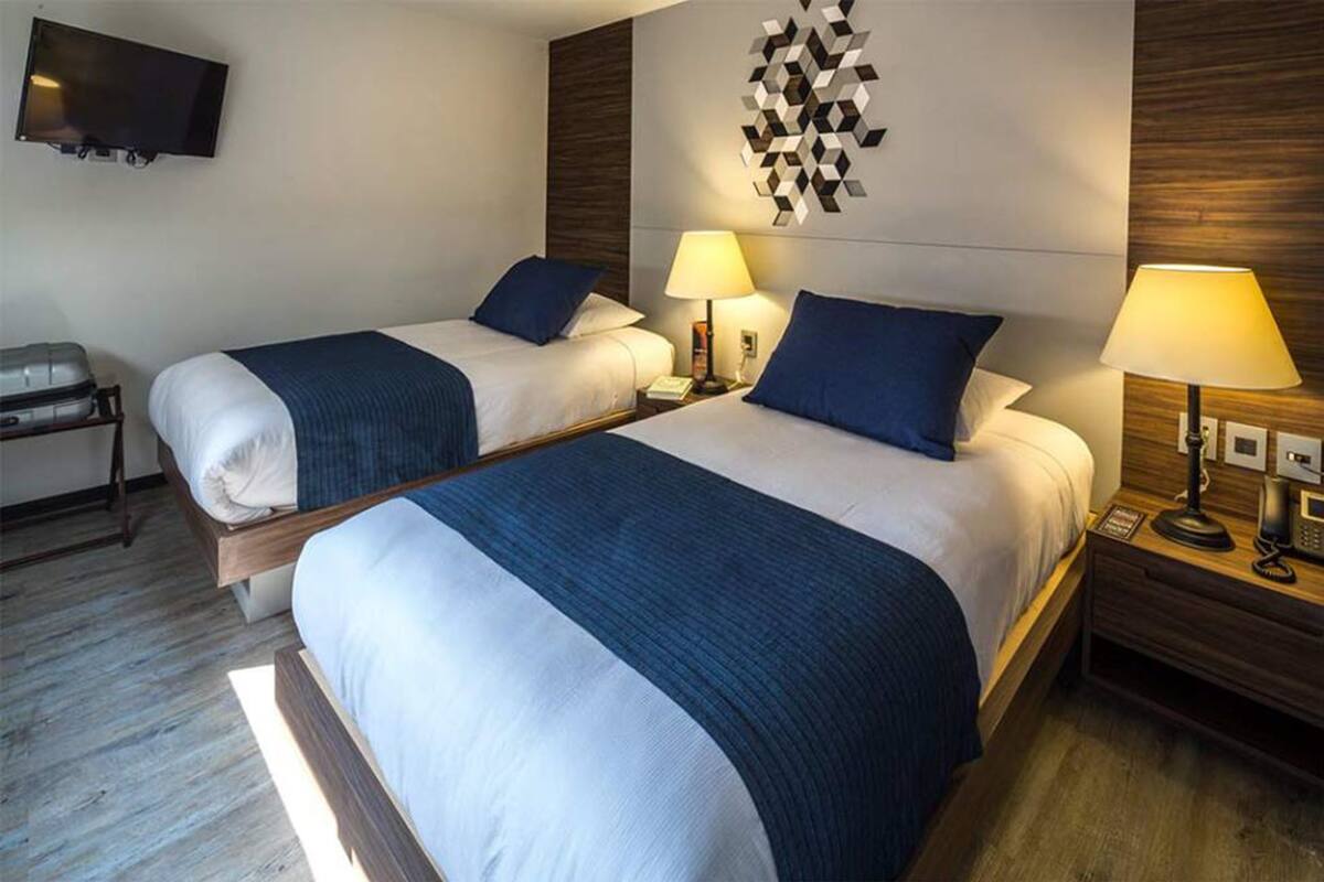 Habitación de hotel con dos camas, un televisor y una obra de arte colgada en la pared.