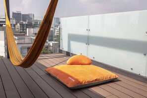Un hamac sur un balcon, avec un matelas et des coussins, d’où l’on peut admirer la vue sur la ville.