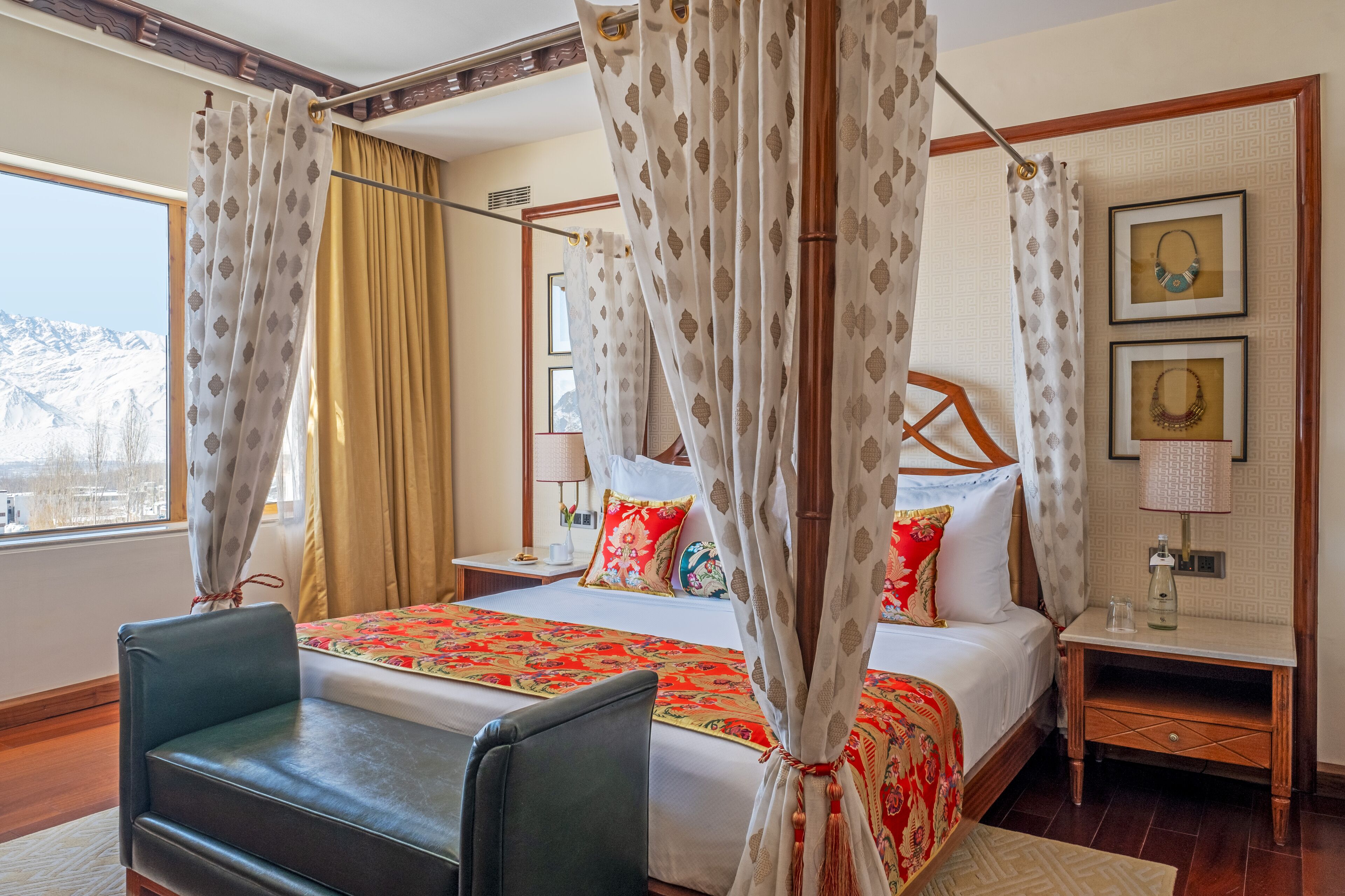 A hotel room with a bed, a chair, a nightstand, a lamp, and a window with curtains.